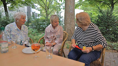 Drei Frauen sitzen draußen im Gespräch