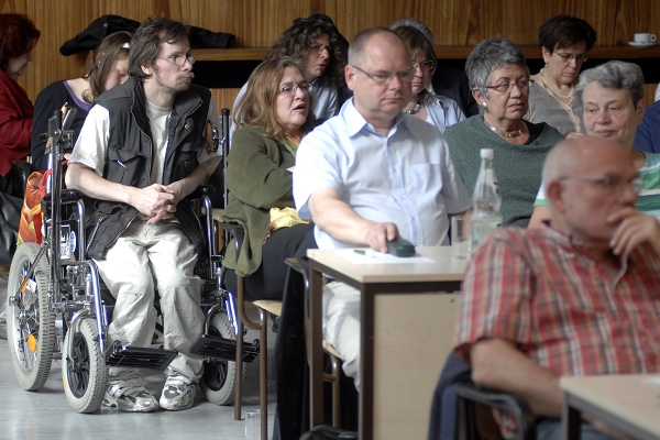 Mann im Rollstuhl hört bei einer Veranstaltung zu. 