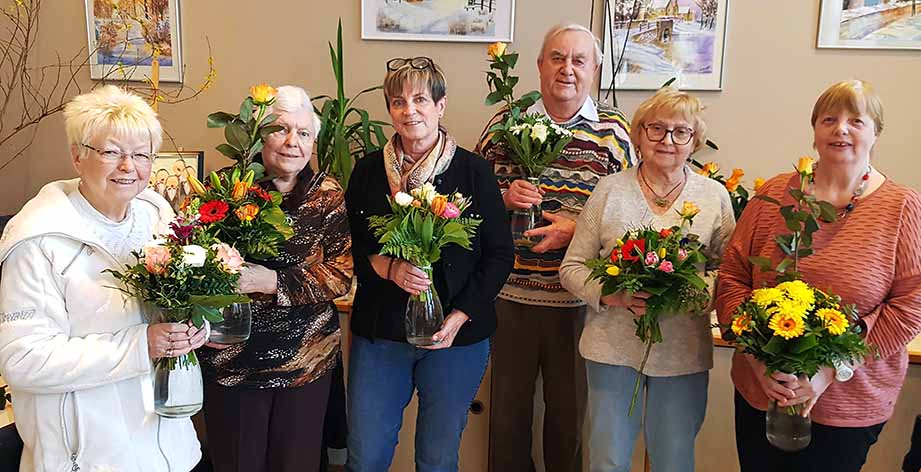 Sechs Personen mit Blumensträußen