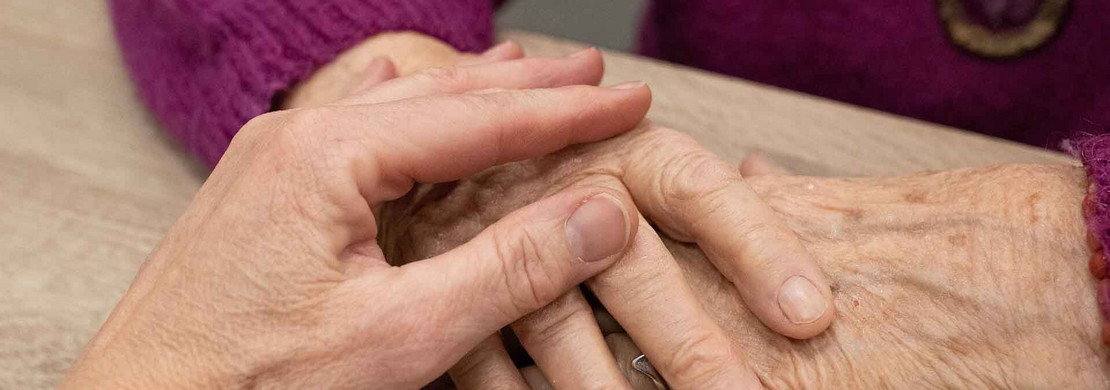 Hand greift nach Händen einer älteren Frau