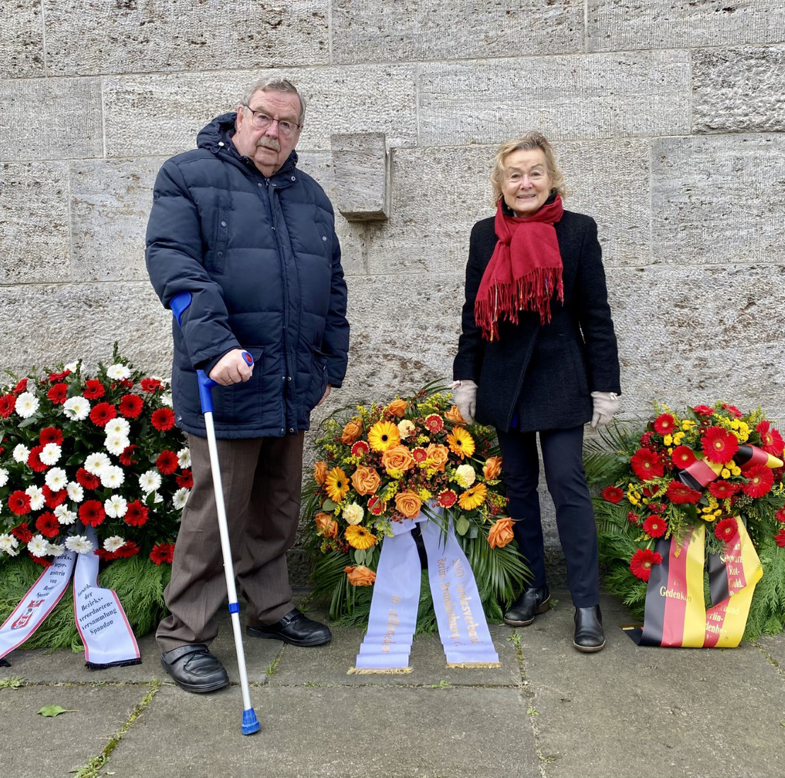Zwei Personen vor Blumenkränzen