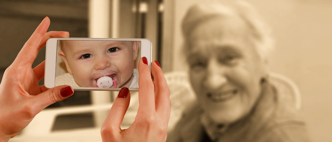 Alte Frau im Hintergrund, Handy mit Babyfoto im Vordergrund. Foto: pixabay