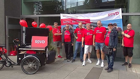Menschengruppe mit einem Lastenrad vor der SoVD-Bundesgeschäftsstelle. 