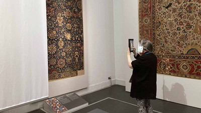 Frau fotografiert einen antiken Teppich