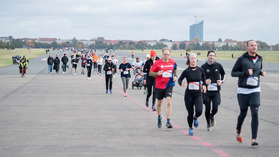 Gruppen von Läuferinnen und Läufern auf dem Tempelhofer Feld in Berlin. 