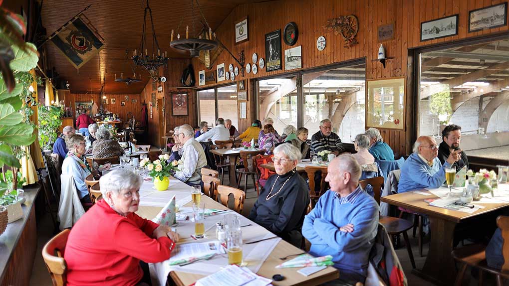 Menschen sitzen an langen Tischen in einer Gaststätte