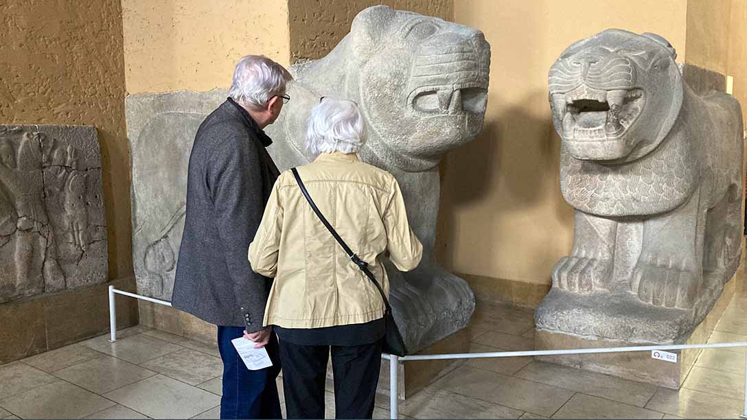 Zwei Menschen betrachten antike Statuen. 